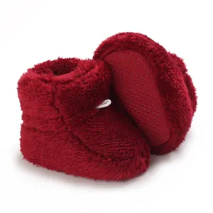 Détail de bottines rouges en peluche pour bébé avec semelle antidérapante et polaire douce.