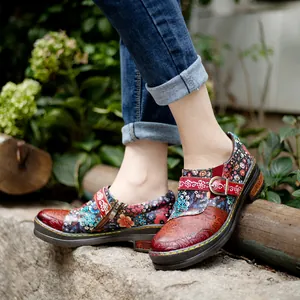 Detailed view of vintage ethnic leather flat shoes with colorful floral prints on feet