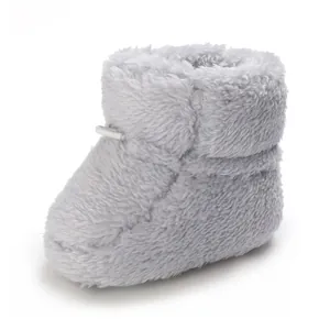 Vue détaillée d'un chausson bébé en peluche grise douce avec texture polaire chaude et cordon
