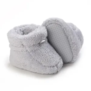Vue détaillée de chaussons bébé en peluche grise avec semelles antidérapantes pour l'hiver