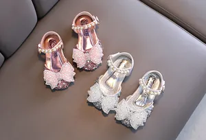 Vue détaillée de chaussures de princesse brillantes pour filles avec nœuds et perles.