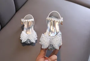 Vue détaillée de chaussures de princesse argentées à paillettes avec nœuds en perles