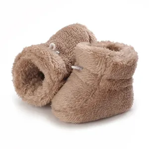 Gros plan de bottines en peluche marron pour bébé avec texture polaire et cordon blanc