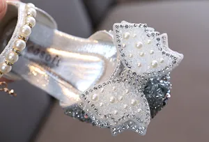 Gros plan détaillé d'un nœud scintillant avec perles sur des chaussures de princesse argentées