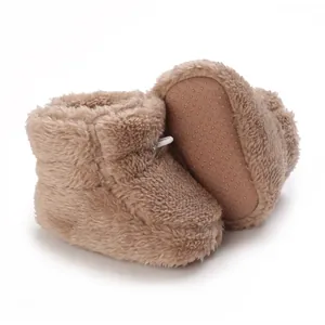 Gros plan de chaussures bébé en peluche marron avec semelle à picots antidérapante