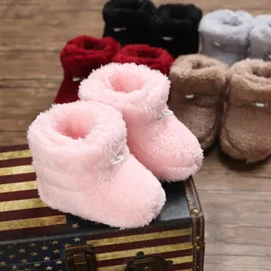 Gros plan de bottines en peluche rose pour bébé sur une boîte décorative, divers coloris.