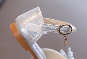 Gros plan de chaussure princesse argentée avec bride velcro, boucle d'or et perles