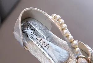 Détail en gros plan de chaussures de princesse argentées avec bride en perles et logo ecosoft