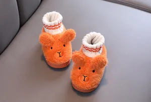 Nahaufnahme von süßen orangefarbenen Plüsch-Babypantoffeln mit Tiergesicht und Strickbündchen