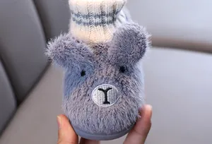 Detailaufnahme eines flauschigen Kleinkinderhausschuhs mit süßem Tiergesicht.