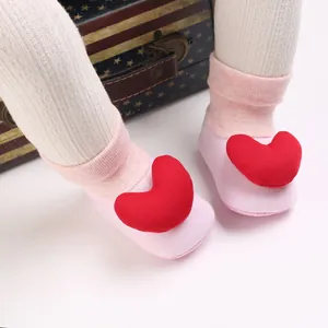 Nahaufnahme von rosa Baby-Laufsocken mit einer dekorativen roten Herz-Applikation