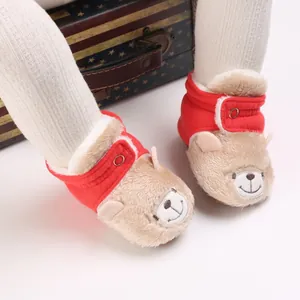Primer plano de botines de peluche para bebé con diseño de oso y suave tela roja