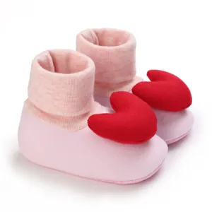 Nahaufnahme von niedlichen rosa Baby-Laufsocken mit großen roten Plüschherz-Dekorationen