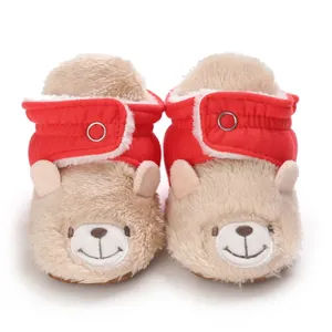 Vista detallada de botas de nieve de peluche para bebé con diseño de oso y correa roja.