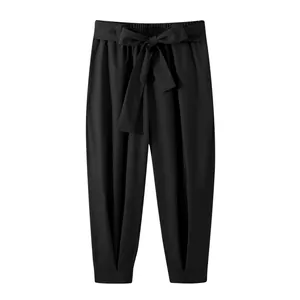 Front view of black loose-fit cropped trousers with a decorative bow belt at the waist