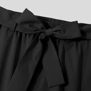 Close-up detail of black casual pants with elastic waist and bow belt decoration.