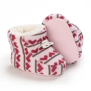 Dettaglio di stivaletti da neve per neonati in maglia rosa con fodera in pile e cuori