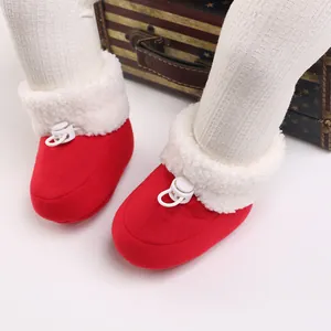 Gros plan de bottines bébé rouges pour l'hiver avec fausse fourrure blanche et cordon