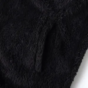 Close-up detail of black fluffy plush fabric and pocket seam on warm fleece jacket