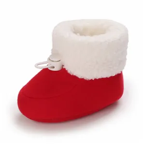 Détail de chaussures d'hiver rouges pour bébé avec doublure en polaire blanche et cordon.