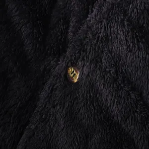 Close-up detail of soft black plush fabric and textured brown button on men's coat