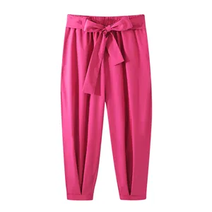Bright pink tapered trousers featuring a stylish waist tie and cuffed leg details.