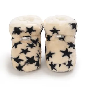Vista detallada de botas de bebé de forro polar cálido con estrellas negras y suelas blandas.