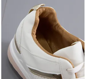 Κοντινό πλάνο λευκών sneakers με πλατφόρμα, χρυσή επένδυση και μεταλλικές λεπτομέρειες.