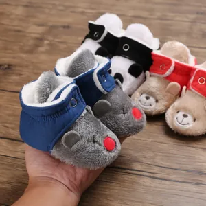 Primer plano de botas de nieve para bebé con caras de animales y forro de pelo.