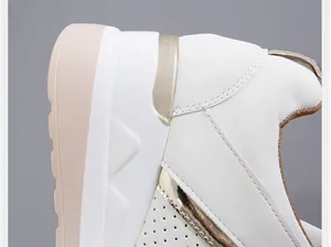Κοντινό πλάνο λευκών γυναικείων sneakers με πλατφόρμα, χρυσές λεπτομέρειες και δέρμα