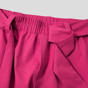 Detailed view of magenta mens trousers showing elastic waistband and tie belt texture