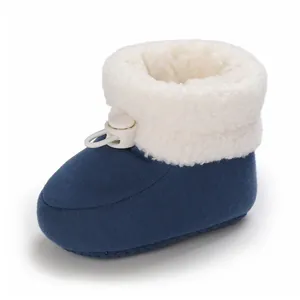 Gros plan d'un chausson bébé bleu marine avec doublure polaire blanche et arrêt de cordon.