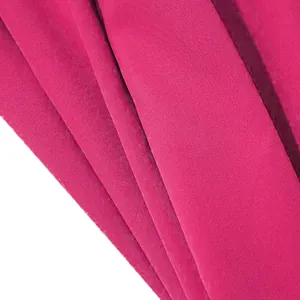 Close-up detail of rose red woven garment fabric showing fine textile weave and texture.