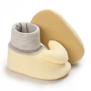 Detailansicht der gelben Baby-Laufsocken mit rutschfester Sohle und Herz-Verzierung.