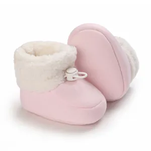 Gros plan de bottines d'hiver roses pour bébé avec doublure en fausse fourrure blanche.