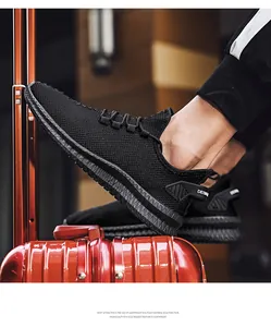Macro view of black breathable fly-knit sneakers resting on a metallic red suitcase