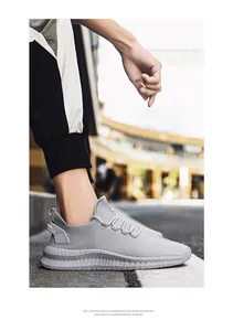 Detailed side view of breathable grey fly-knit men's sneakers with lightweight EVA sole.