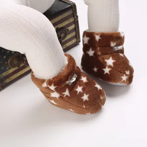 Primer plano de botas de felpa marrón para bebé con patrones de estrellas blancas