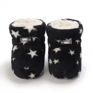 Detalle de botas de felpa para bebé con estampado de estrellas blancas y negras y cierre