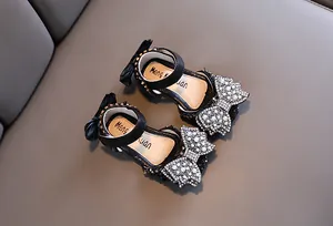 Detailansicht von schwarzen Prinzessinnen-Sandalen für Mädchen mit glitzernden Schleifen