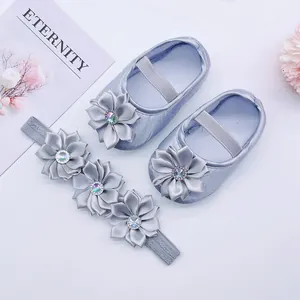 Close-up of silver baby princess shoes and matching satin flower headband set.