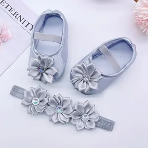 Macro view showing silver satin baby shoes and floral headband set with rhinestone details