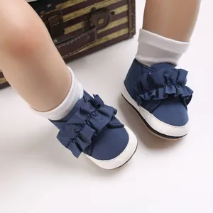 Nahaufnahme der dunkelblauen Baby-Lauflernschuhe mit Rüschendetails auf weißen Socken.