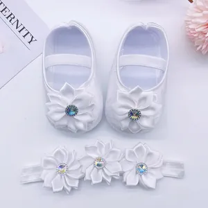 Detailed macro shot of white infant princess shoes with matching floral headband set