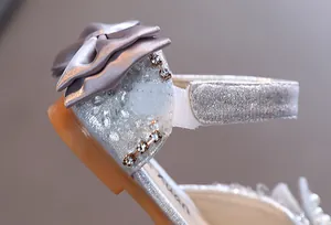 Detailansicht Mädchen Sandalen mit Satin-Schleife und Strass auf glitzerndem Stoff