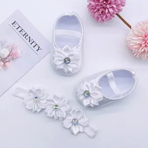 Detailed shot of white satin baby princess shoes and matching floral headband set