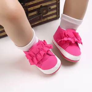 Detailansicht rosa Babyschuhe mit Rüschenverzierung und weißer Gummisohle für Kleinkinder.