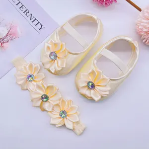 Close-up of cream satin baby princess shoes and matching flower rhinestone headband set