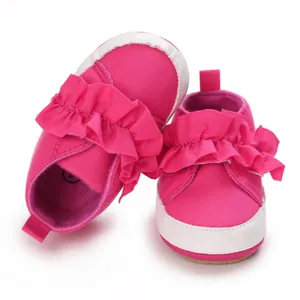 Nahaufnahme von rosa Baby-Lauflernschuhen mit Rüschendetails und weicher Sohle für Kleinkinder