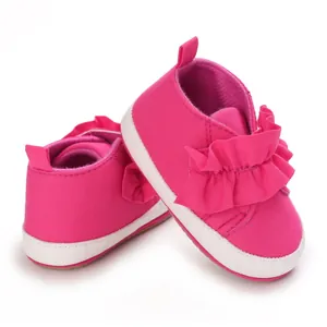 Detailaufnahme der rosa Lauflernschuhe mit Rüschenverzierung und weicher Stoffsohle.
